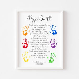 May include: A framed print with a white border features a poem and colorful handprints. The text reads "Miss Smith" at the top, followed by a thank you message and the names "Ellie and Faye" with the year "2022-2023" at the bottom.