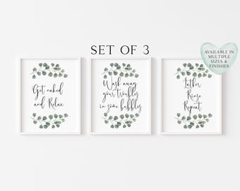 May include: A set of three white-framed wall art prints featuring green eucalyptus leaf illustrations. The text reads: Get naked and Relax, Wash away your troubles in some bubbles, and Lather Rinse Repeat. The top centre text says SET OF 3.