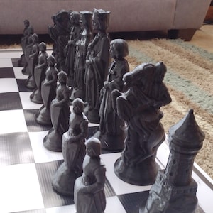 May include: A black and white chess set with various pieces, including a king, queen, knight, bishop, rook, and pawn. The pieces are made of plastic and have a detailed design. The set is arranged on a black and white checkered board.