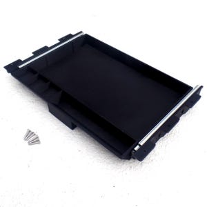 May include: Black plastic tray with a sliding drawer and compartments. The tray is designed to hold small items and includes screws for installation.