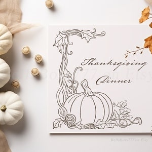 May include: A Thanksgiving-themed image featuring a white card with a pumpkin illustration and the words "Thanksgiving Dinner." Three white pumpkins and decorative elements are arranged around the card. Dried leaves and small wooden accents complete the autumn aesthetic.