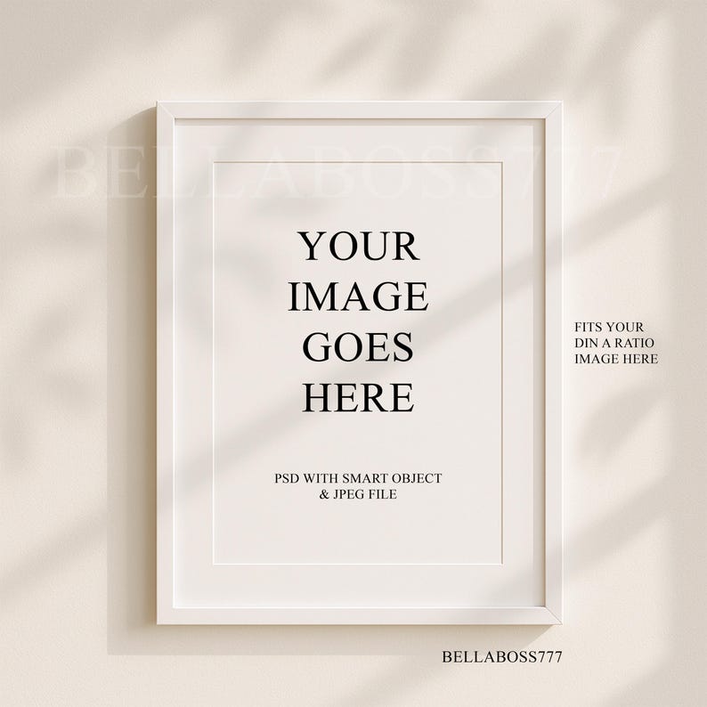 May include: White frame mockup with the text "YOUR IMAGE GOES HERE" and "FITS YOUR DIN A RATIO IMAGE HERE". The text "PSD WITH SMART OBJECT & JPEG FILE" is also included. The frame is on a beige wall with shadows.