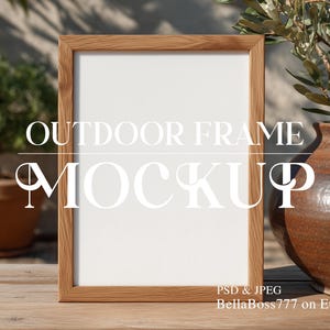 May include: A wooden picture frame mockup with a white interior, set outdoors on a wooden surface. The frame is surrounded by greenery, including a potted plant and a decorative vase. The text "OUTDOOR FRAME MOCKUP" is displayed on the frame.