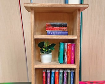 May include: A miniature wooden bookshelf with three shelves. The top shelf has a stack of four books with the titles "Crescent City", "House of Earth and Blood", and "A Court of Thorns and Roses". The middle shelf has a small potted plant and a stack of seven books with the titles "Throne of Glass", "Crown of Midnight", "Heir of Fire", "A Court of Thorns and Roses", "A Court of Mist and Fury", "A Court of Wings and Ruin", and "Silver Flames". The bottom shelf has a row of twelve books with the titles "Throne of Glass", "Tower of Dawn", "Heir of Fire", "Crown of Midnight", "The Assassin's Blade", "Empire of Storms", "The Empire of Storms", "The Assassin's Blade", "A Court of Wings and Ruin", "A Court of Mist and Fury", "A Court of Thorns and Roses", and "The Cruel Prince".