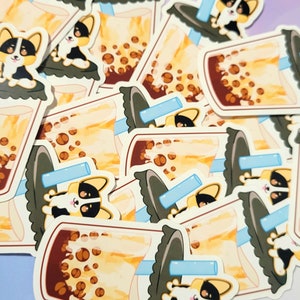 May include: A selection of stickers depicting a cartoon corgi dog with bubble tea. The stickers show a clear plastic cup with brown tapioca pearls, a blue straw, and a corgi dog. The corgi is black, white, and tan.