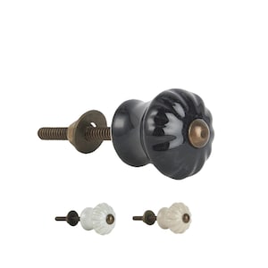 Könnte beinhalten: Ein Satz von drei Keramik-Schrankknöpfen mit geriffeltem Design. Die Knöpfe sind in Schwarz, Weiß und Creme erhältlich.