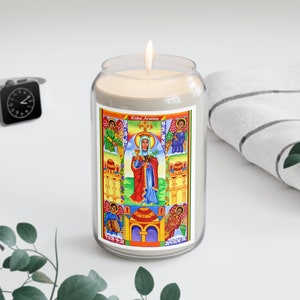 May include: A glass candle jar with a white candle inside. The jar has a colorful label with an image of a woman in a red robe and a crown, surrounded by other figures. The label also includes the text "Kidist Mariam".