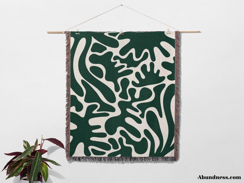 May include: A green and white woven wall tapestry with an abstract pattern of organic shapes. The tapestry has a fringe border.