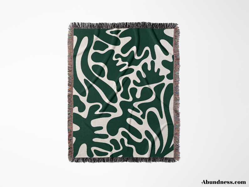 May include: A woven throw blanket with a green and white abstract pattern. The pattern features organic shapes and lines.