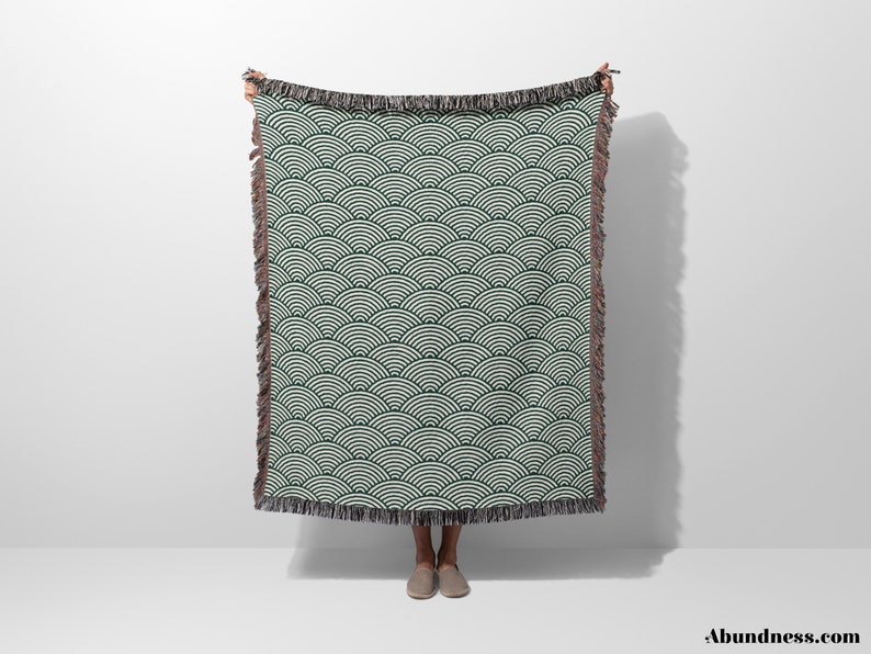 May include: A dark green and white patterned throw blanket with a wave design. The blanket has a fringed edge and is displayed against a white backdrop. The word "Abundance" is visible in the bottom right corner.