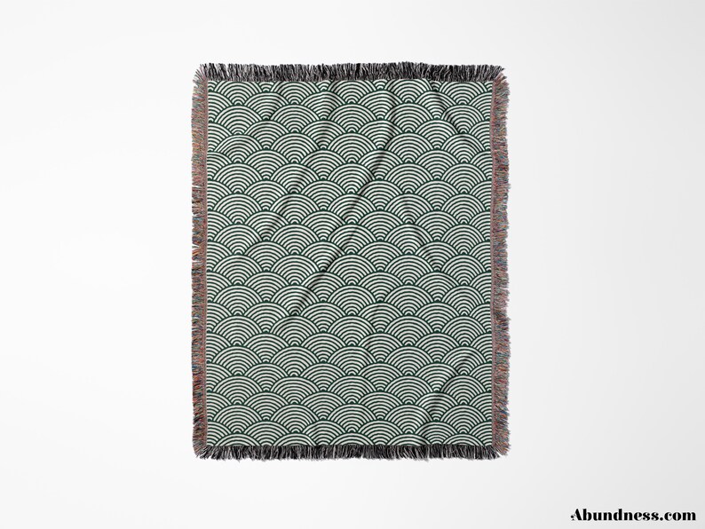 May include: A rectangular throw blanket featuring a repeating wave pattern in dark green and white. The blanket has a fringed edge in shades of brown and black. The design covers the entire surface of the blanket.