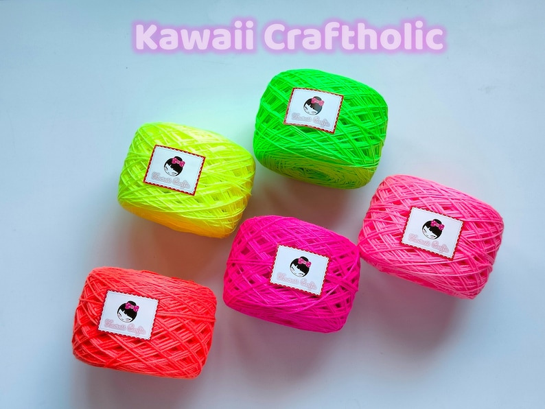 May include: Five balls of neon yarn in green, yellow, pink, and two shades of orange. Each ball has a white label with a cartoon girl and the text "Kawaii Craft".