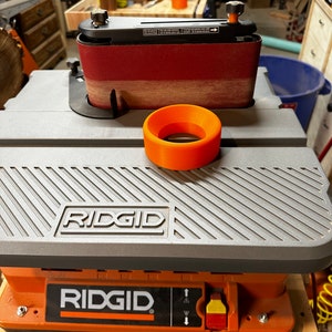 May include: A gray and orange Ridgid belt sander with a sanding belt and a round orange sanding guide. The sander has a black power switch with a red and yellow button.