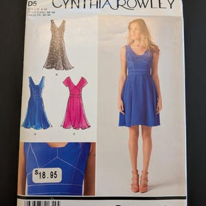 May include: A Simplicity sewing pattern featuring a Cynthia Rowley design. The pattern includes illustrations of dresses in various styles and colors, with the text "1654 D5" and "Simplicity" visible. The price tag shows $18.95.