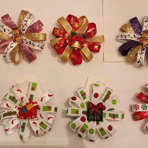 以下が含まれることがあります： さまざまなデザインのクリスマスをテーマにしたヘアボウが10個。赤と白のキャンディーケーン、雪だるま、サンタクロース、トナカイなどがあります。リボンとグリッターで作られています。