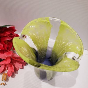 May include: A green and blue glass vase with a unique, wavy design. The vase has a wide opening and a narrow base.