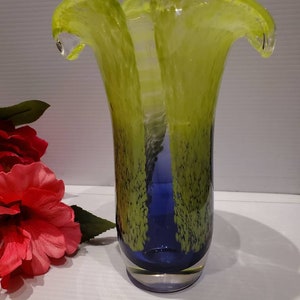 May include: A glass vase with a wide, flared opening and a narrow base. The vase is made of clear glass with a blue and green swirl pattern.