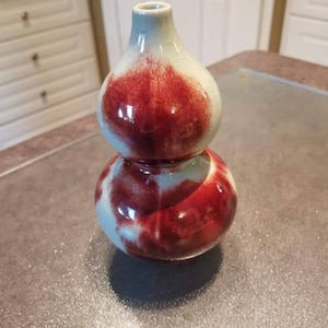 Può includere: Un vaso a doppia zucca con una glassa rossa e bianca. Il vaso è in ceramica e ha un design cinese tradizionale.