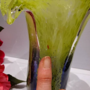 May include: A green and blue glass vase with a wavy, ruffled top. The vase has a textured surface and a mottled appearance.