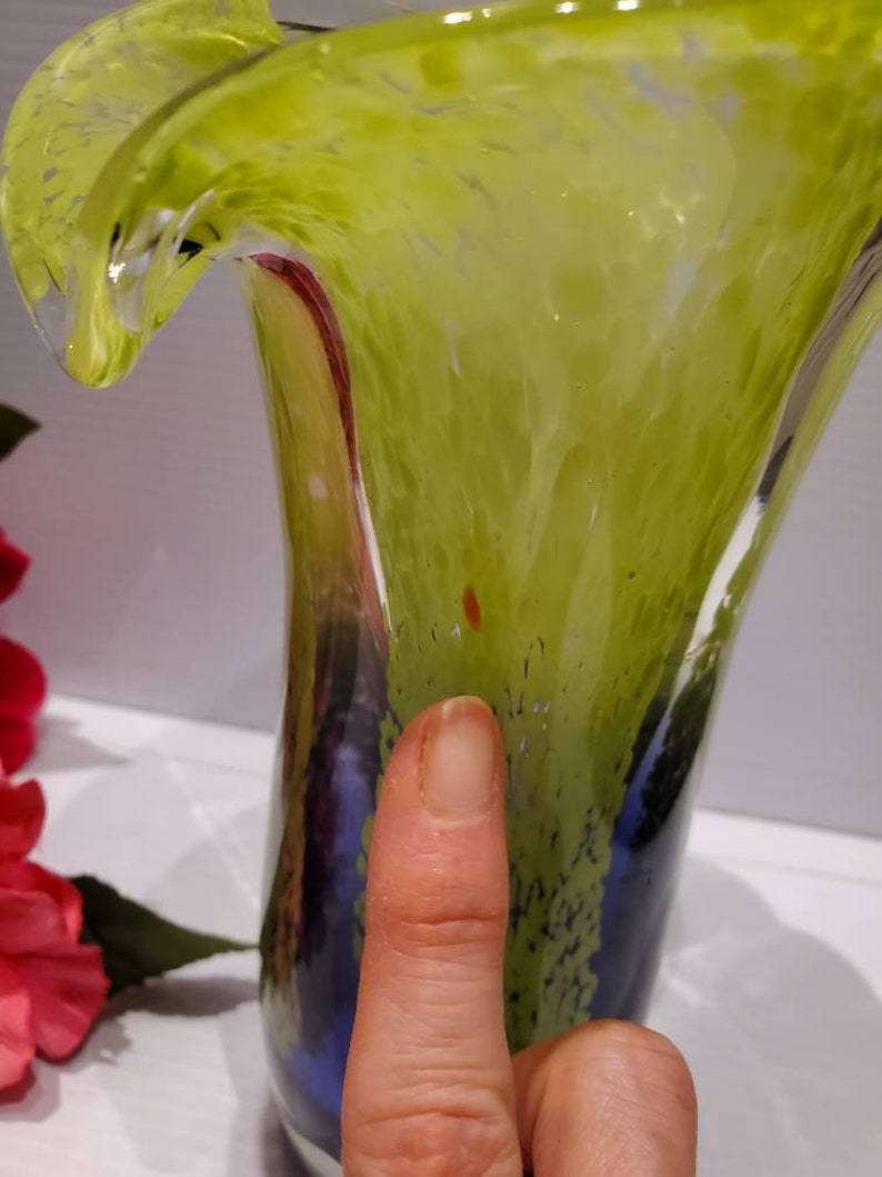 May include: A green and blue glass vase with a wavy, ruffled top. The vase has a textured surface and a mottled appearance.
