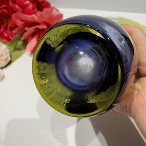 May include: A dark blue glass bottle with a yellow rim. The bottle is round and has a smooth surface.