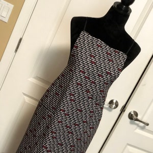 以下が含まれることがあります： 全体に「love」という単語が白と赤で繰り返しプリントされた黒いマキシ丈ワンピース。細いストラップとスクエアネックラインが特徴です。