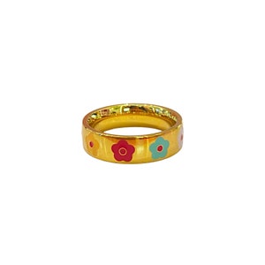 May include: A gold ring with a band of colorful enamel flowers. The flowers are yellow, red, and blue.