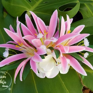 May include: Pink and white flower lei with green leaves. The lei is made of silk flowers and is perfect for a luau or other tropical event.