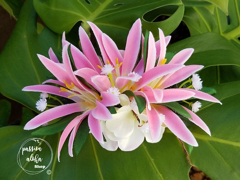 May include: Pink and white flower lei with green leaves. The lei is made of silk flowers and is perfect for a luau or other tropical event.