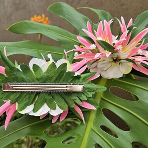 May include: Two pink and white flower hair clips with green leaves. The clips have a silver metal bar.