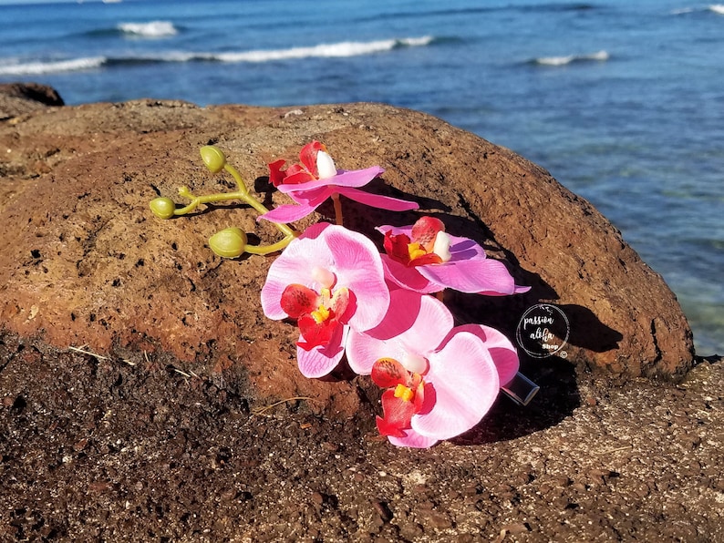 May include: Pink orchid flower hair clip with a clear acrylic charm that says "passion elite".