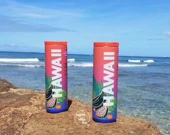 May include: Two cylindrical water bottles with a pink and orange gradient, the word "HAWAII" in white, and tropical fruit illustrations. The bottles have orange lids and are set against the ocean and blue sky.