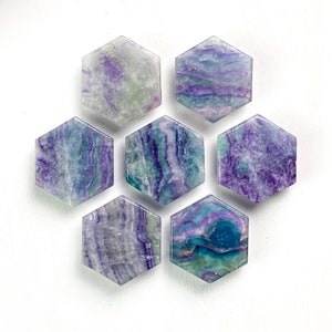 May include: Six hexagonal fluorite coasters in shades of purple, blue, and green. The coasters are arranged in a honeycomb pattern.