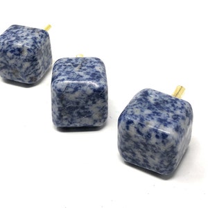 May include: Three blue and white marble cabinet knobs with gold metal accents. The knobs are square shaped and have a speckled pattern.