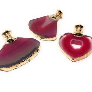 May include: Three agate drawer pulls with gold trim. The pulls are in the shapes of a heart and two half circles. The agate is pink and white with a natural, raw edge.