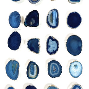 May include: Twenty blue agate slices with gold trim. Each slice has a unique pattern of blue and white agate.