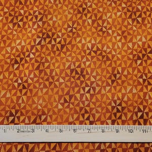 May include: Orange fabric with a geometric pattern of white triangles. The fabric is measured with a ruler that reads "Made in U.S.A."