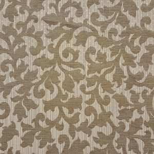 May include: A close-up of a brown fabric with a white damask pattern. The fabric has a subtle sheen and a textured surface.