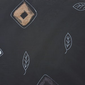 May include: Black fabric with a repeating pattern of white leaves and brown and white diamond shapes.