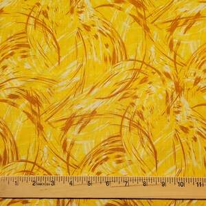 May include: Yellow fabric with a swirling pattern of brown lines. The fabric is measured with a ruler that shows 13 inches.