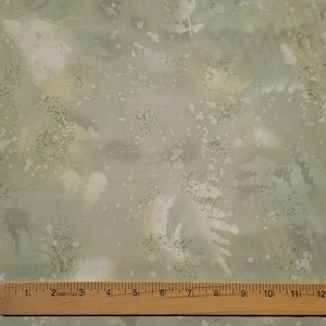 May include: A close-up of a light green fabric with a white and gray mottled pattern. The fabric has a subtle texture and a soft, faded look.