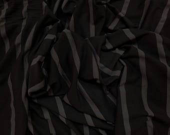 May include: Black and gray striped fabric with a soft, textured feel. The fabric is draped and folded, showing the texture and pattern.