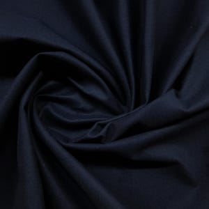 May include: A close-up shot of a dark navy blue fabric with soft folds and shadows. The fabric appears to be a solid color, with a smooth texture. The image highlights the material's drape and depth, suitable for apparel or home decor.
