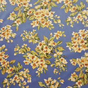 May include: A blue fabric with a repeating pattern of yellow flowers and green leaves.