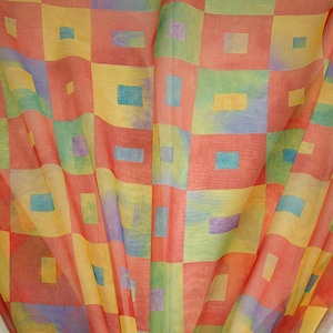 May include: A sheer fabric with a checkered pattern in shades of red, yellow, green, and blue. The fabric is folded in the center, creating a wave-like effect.