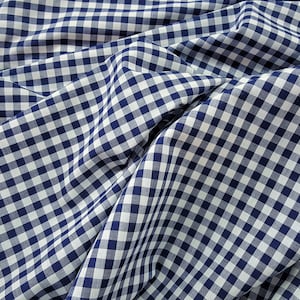 May include: A close-up of a white and navy blue gingham fabric. The fabric is folded and has a soft, textured appearance.