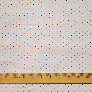 May include: White fabric with a pattern of small, colorful polka dots in red, blue, orange, and green. A wooden ruler with inch markings is at the bottom, measuring up to 12 inches.