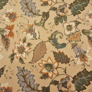 May include: A beige fabric with a repeating pattern of stylized flowers in shades of green, blue, brown, and white.