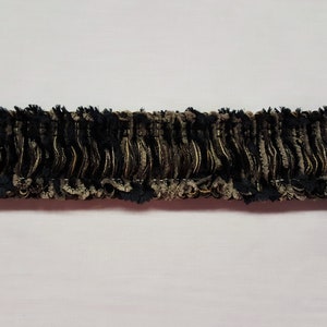 May include: Black and gold trim with a ruffled texture. The trim is made of a soft, fuzzy material.