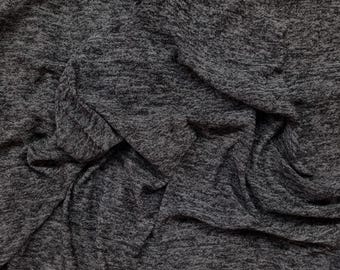 May include: Close-up of a gray and black textured fabric with a crinkled and folded appearance.